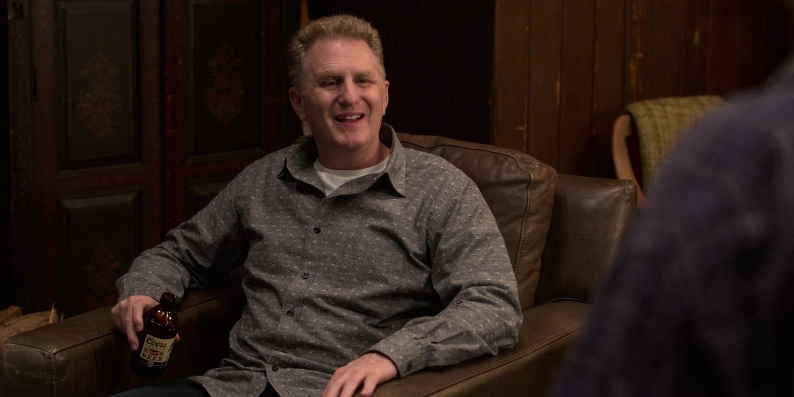 Doug Gardner drinks a beer and sits in an armchair with a smile in Atypical