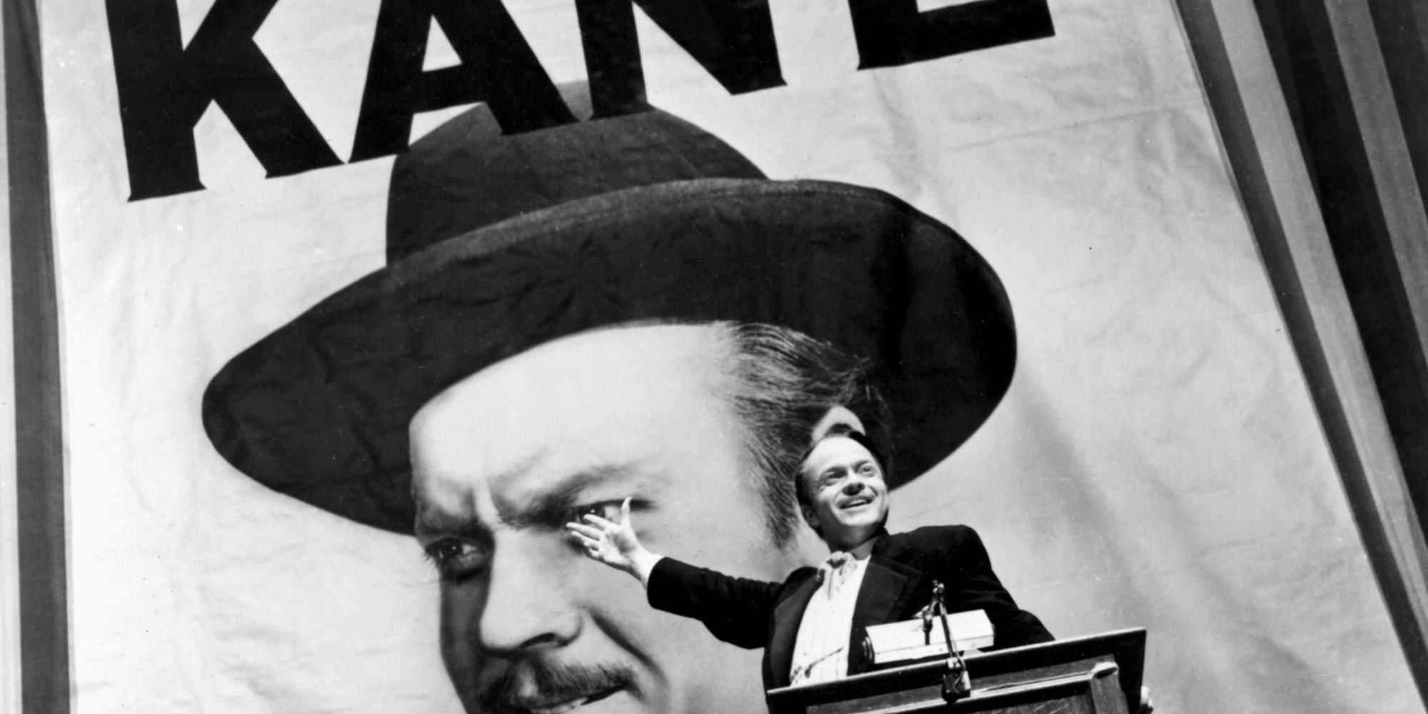 Charles Foster Kane in Citizen Kane standing in front of a huge poster of himself