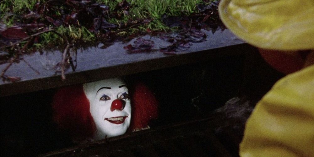 Pennywise the clown in the gutter looking out in It.