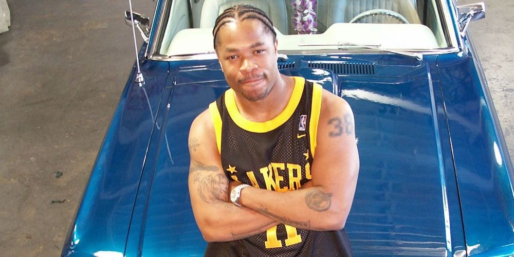 Xzibit folding his arms while leaning on a car in Pimp My Ride