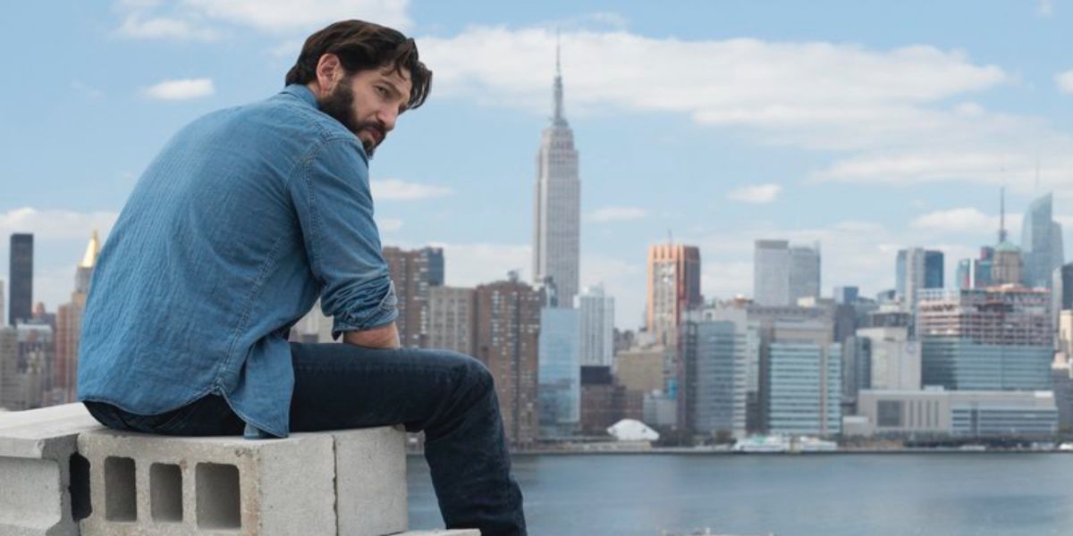 Frank Castle sitting on concrete blocks overlooking city in The Punisher