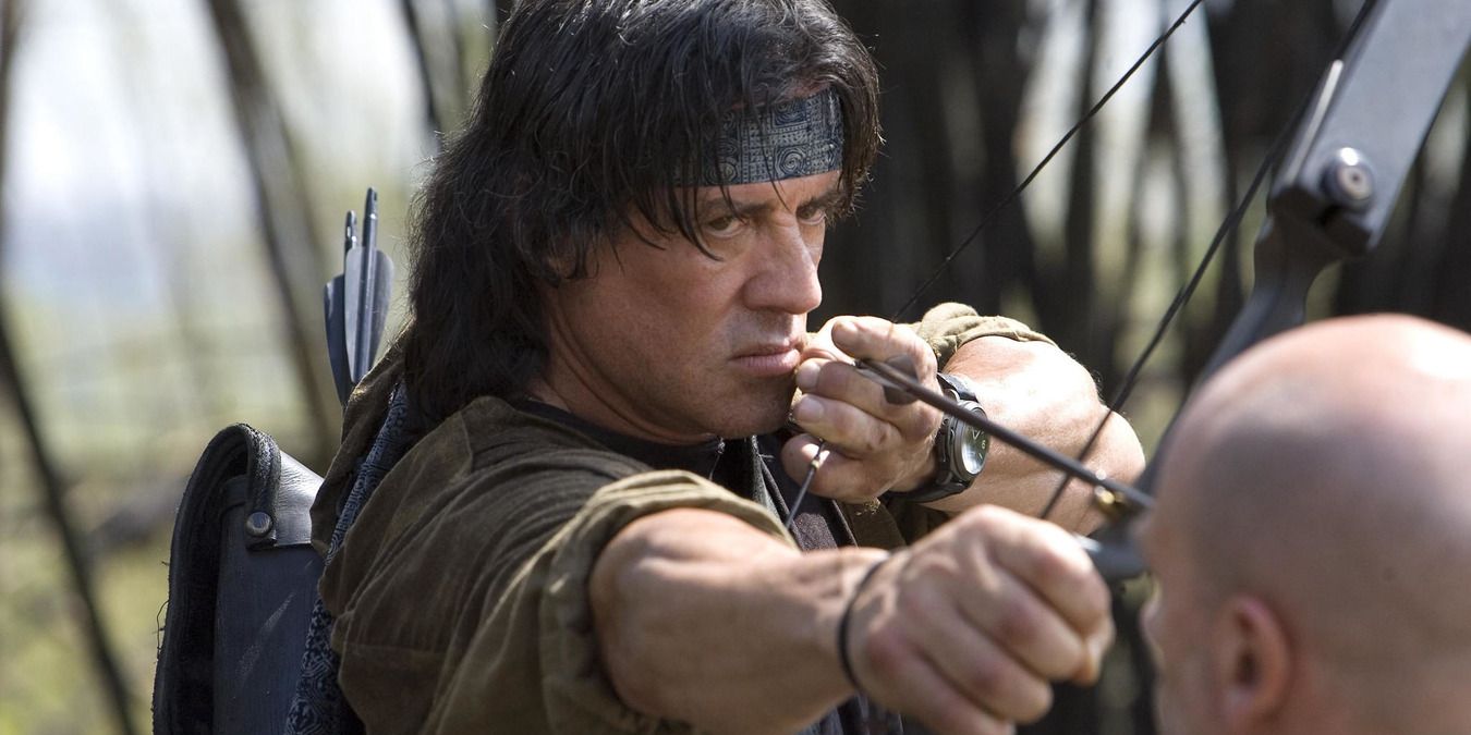 Rambo holding a bow and arrow, aimed at a man's head in Rambo 2008