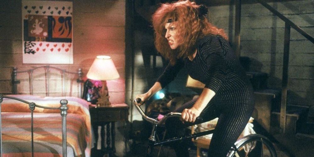 Barbara Stone riding on a exercise bike and scowling in Ruthless People
