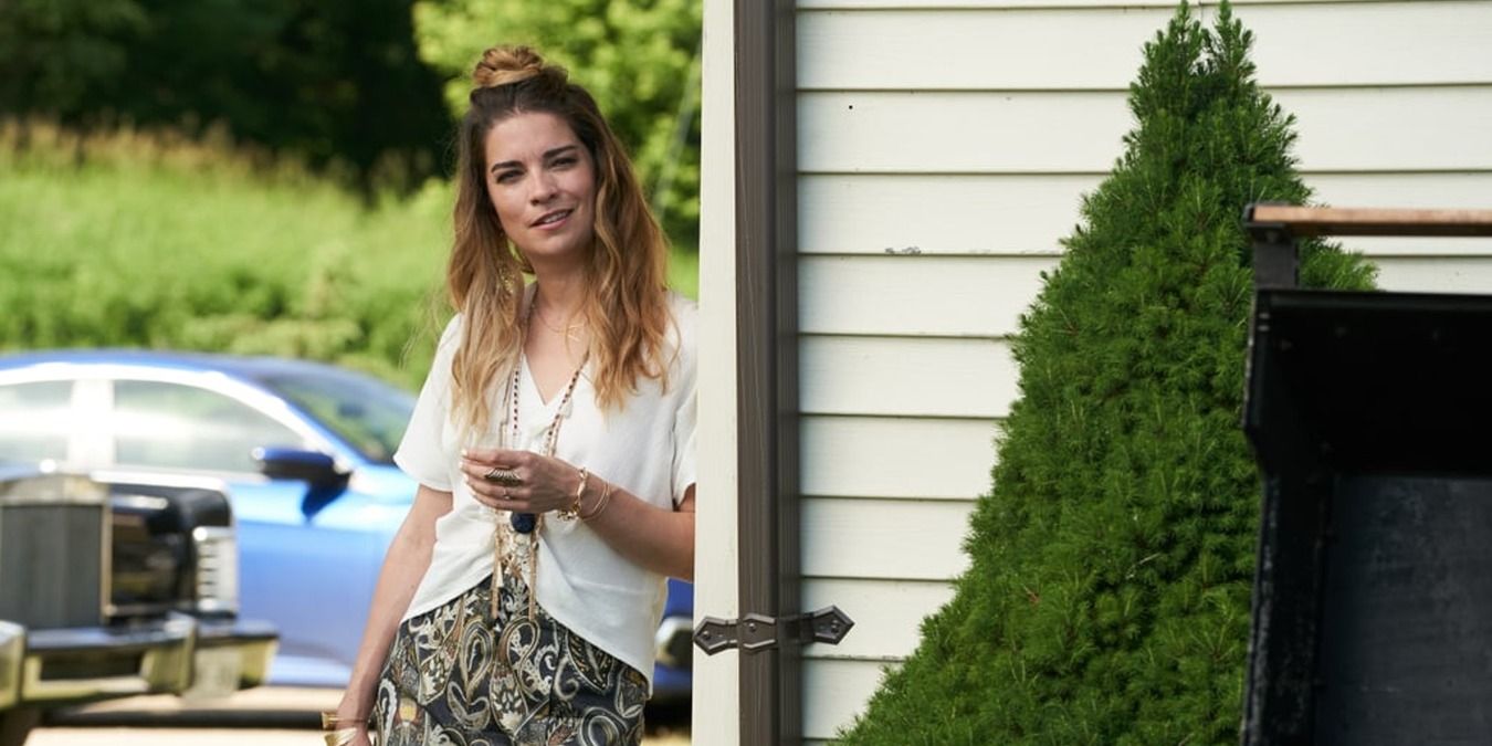 Alexis leands against a wall outside the motel in Schitt's Creek