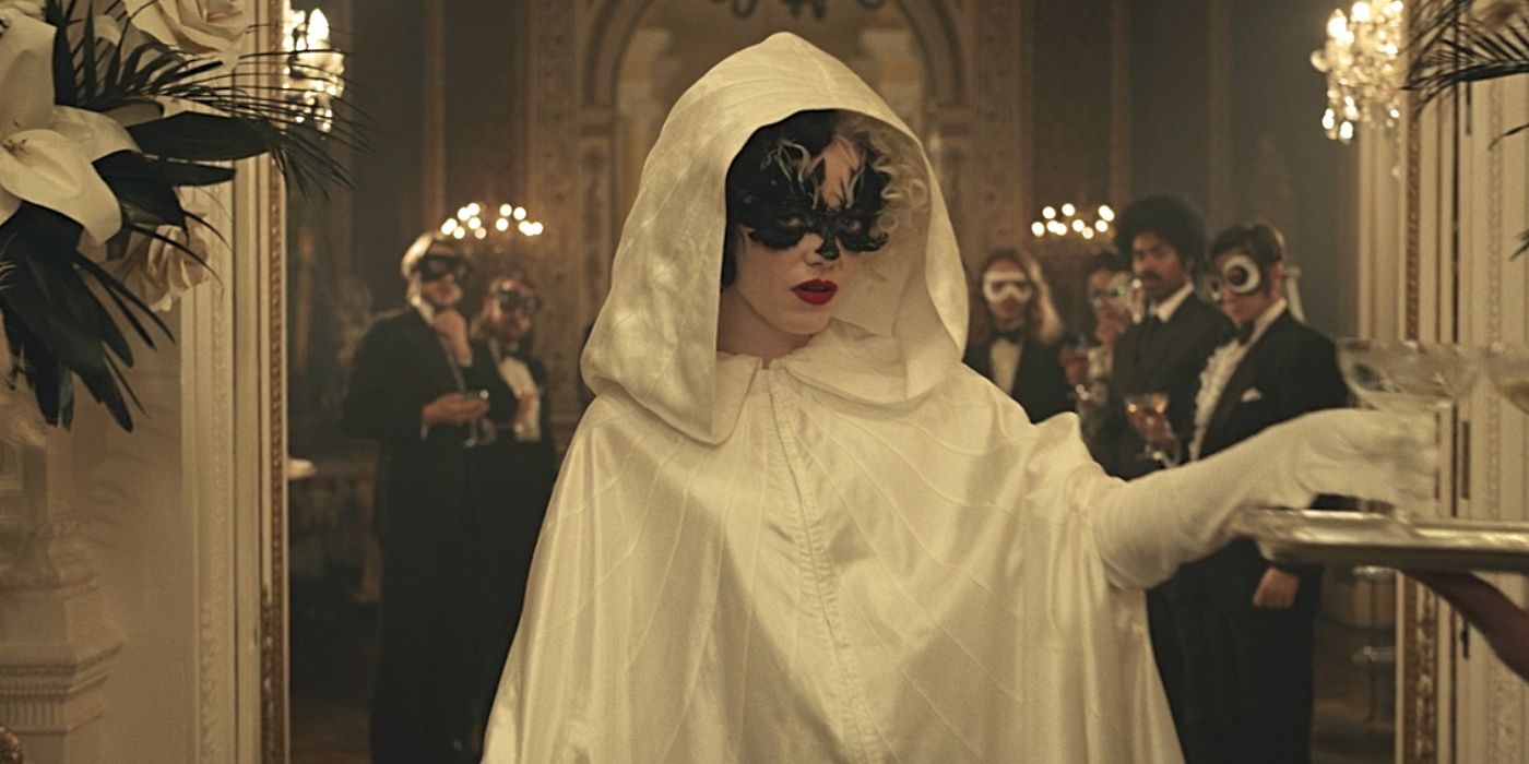 Emma Stone em Cruella vestindo capa branca e máscara
