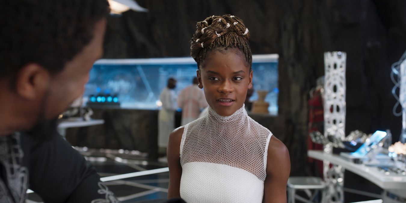 Shuri em pé no laboratório, conversando com T'Challa em Pantera Negra. 