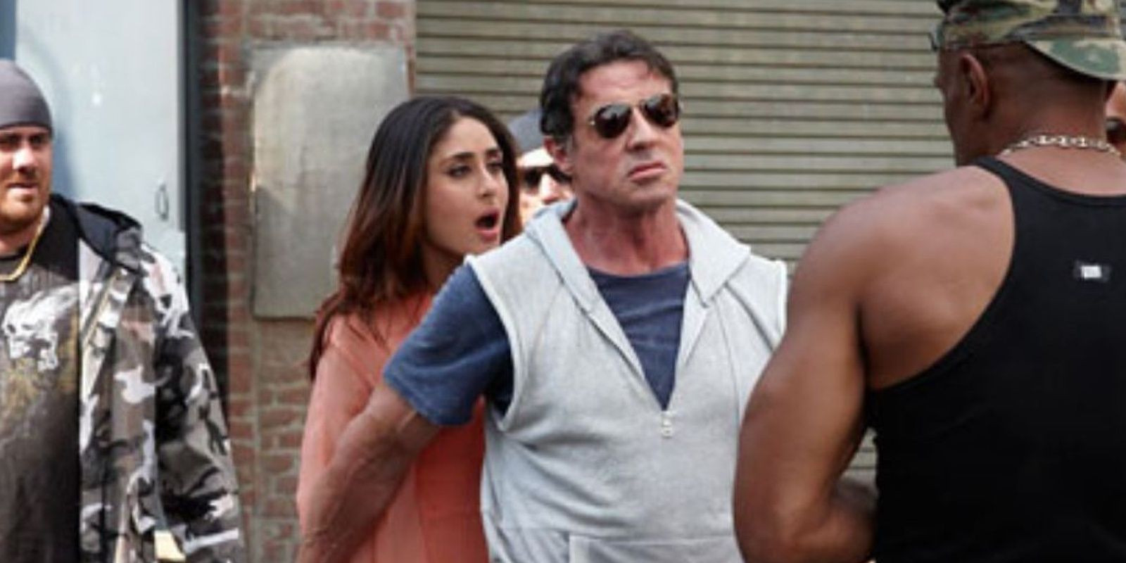 Sylvester Stallone gesturing Kareena Kapoor to stand behind him as he prepares to fight hooligans in a still from Kambhakkht Ishq
