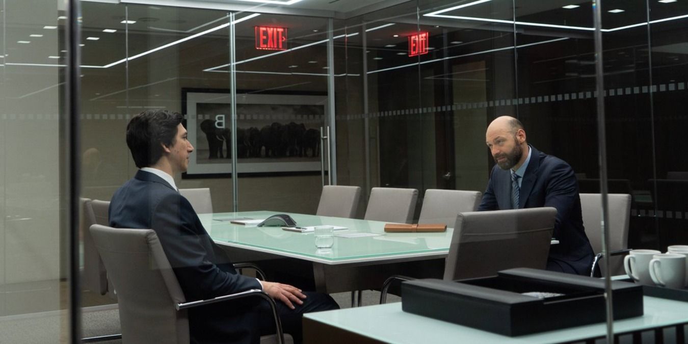 The Report - Daniel (Adam Driver) sitting across a table from Cyrus (Corey Stoll) in the office