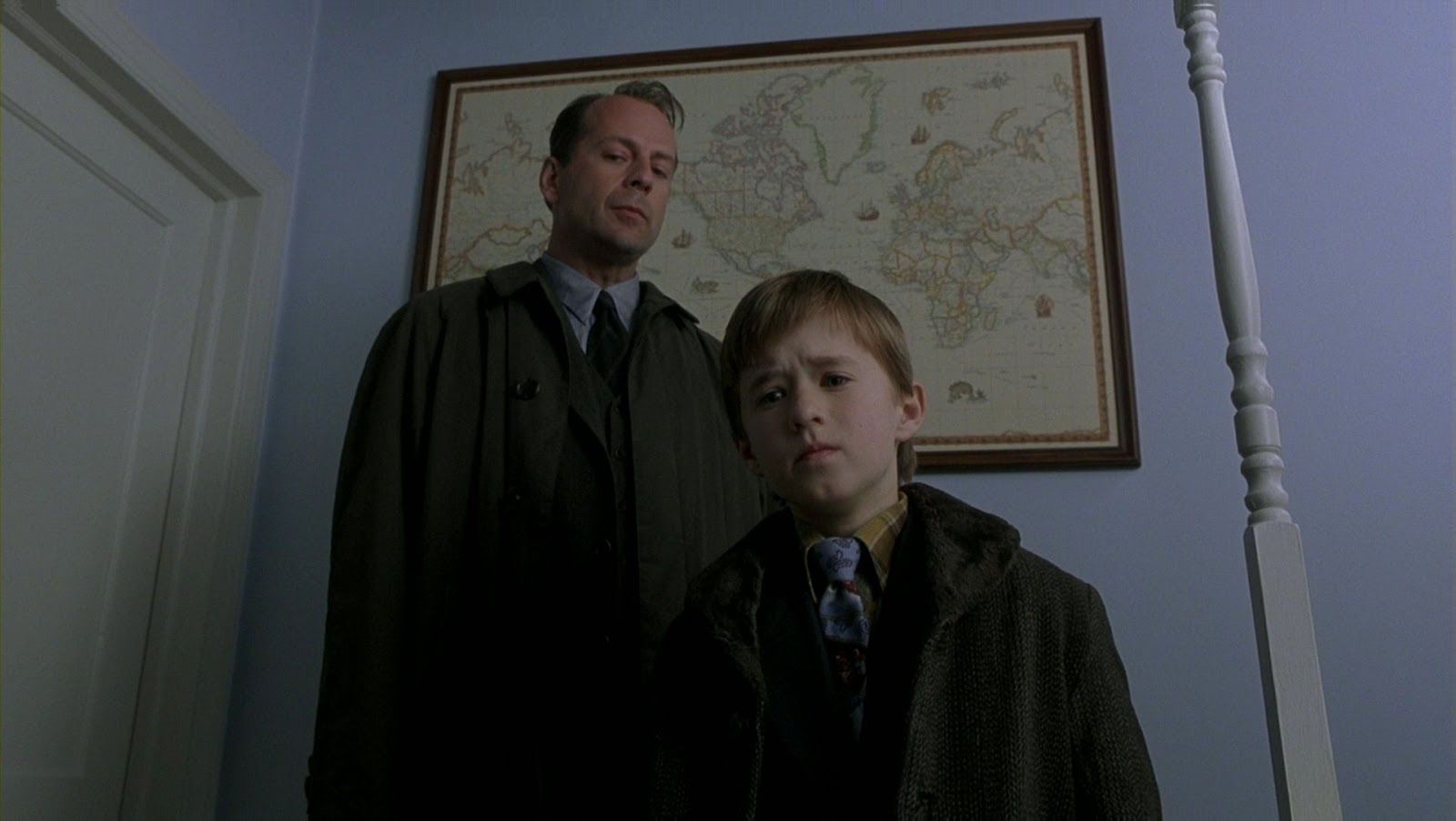 Hailey Joel Osment and Bruce Willis in The Sixth Sense stand side by side in a bedroom, looking troubled.