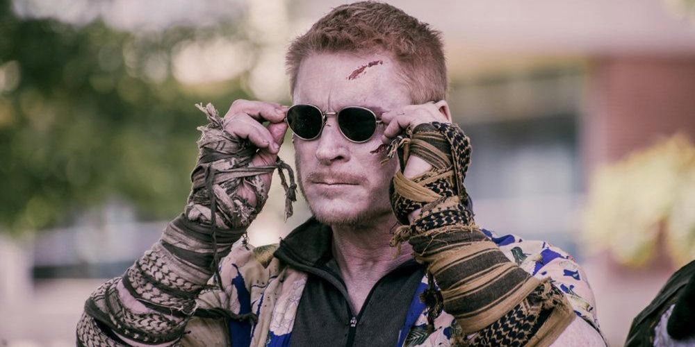 An image of Zack Ward adjusting his sunglasses and wearing neckerchief bracelets in Z Nation