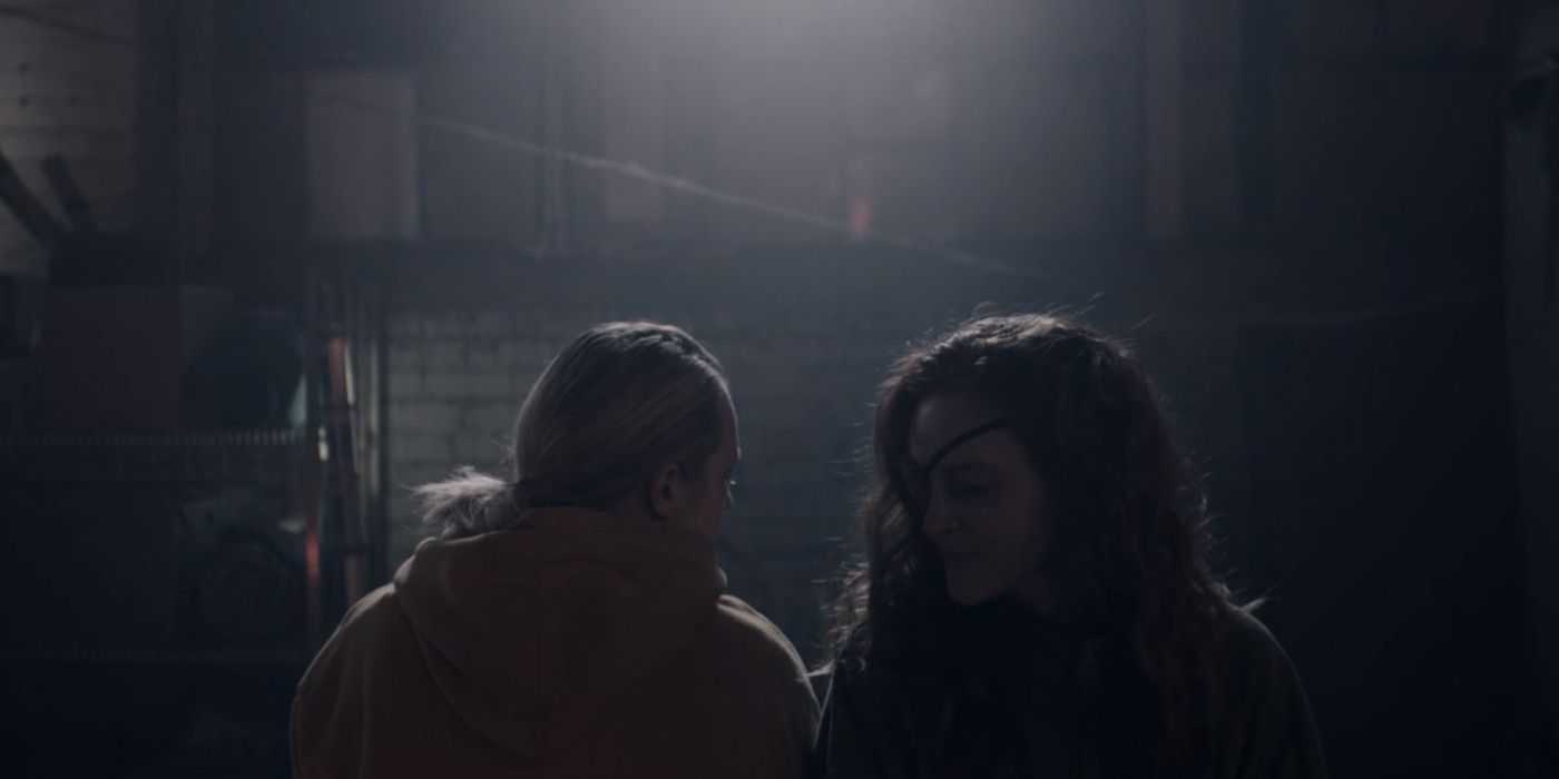 June and Janine sitting opposite ways on a bench in the dark on The Handmaid's Tale