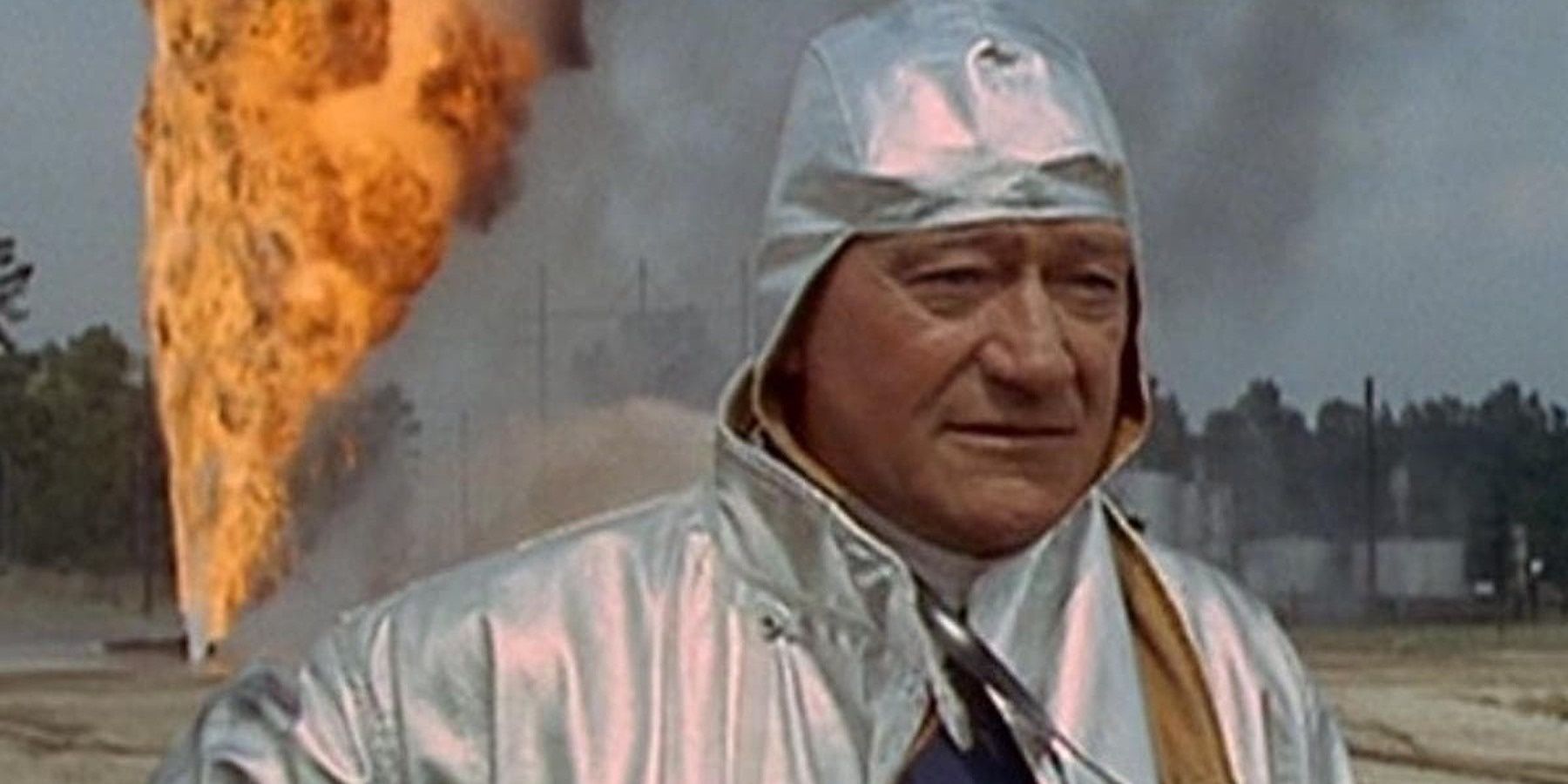 John Wayne wearing flame retardent suit with fire behind him in Hellfighters.