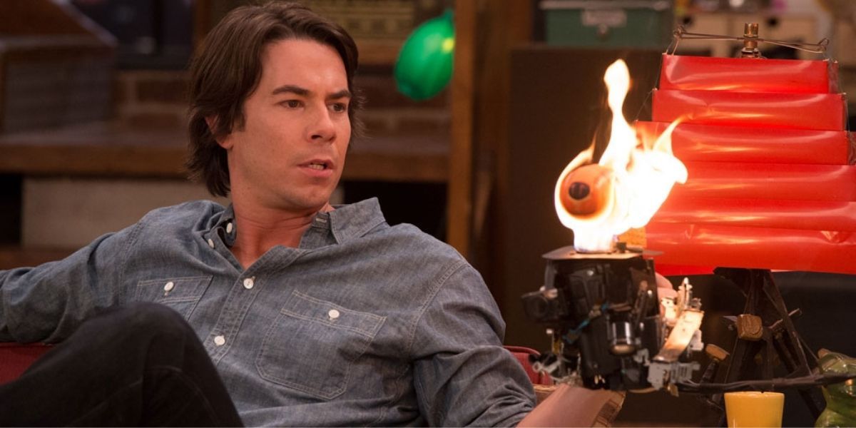 Spencer holding one of his art piece that is on fire in iCarly.