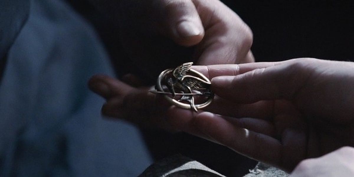 Katniss holds her Mockingjay pin in The Hunger Games