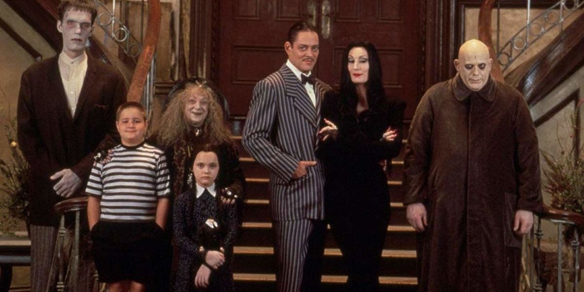 The Addams Family stand by the stairs in The Addams Family