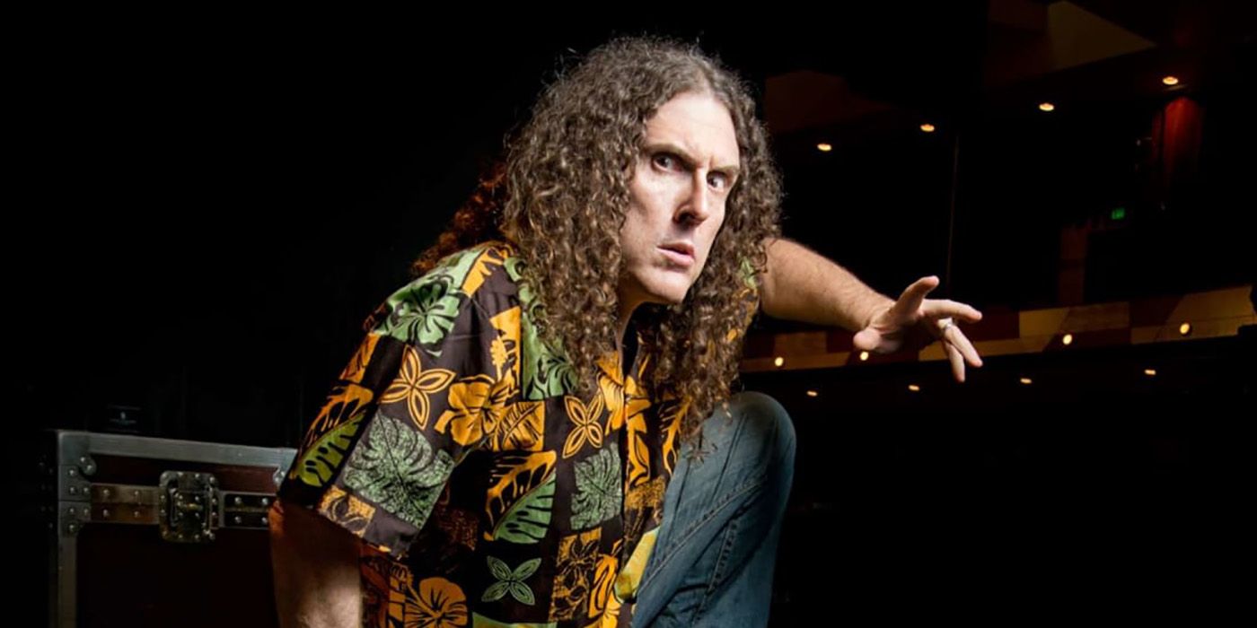 Weird Al Yankovic in a loud shirt on a black background