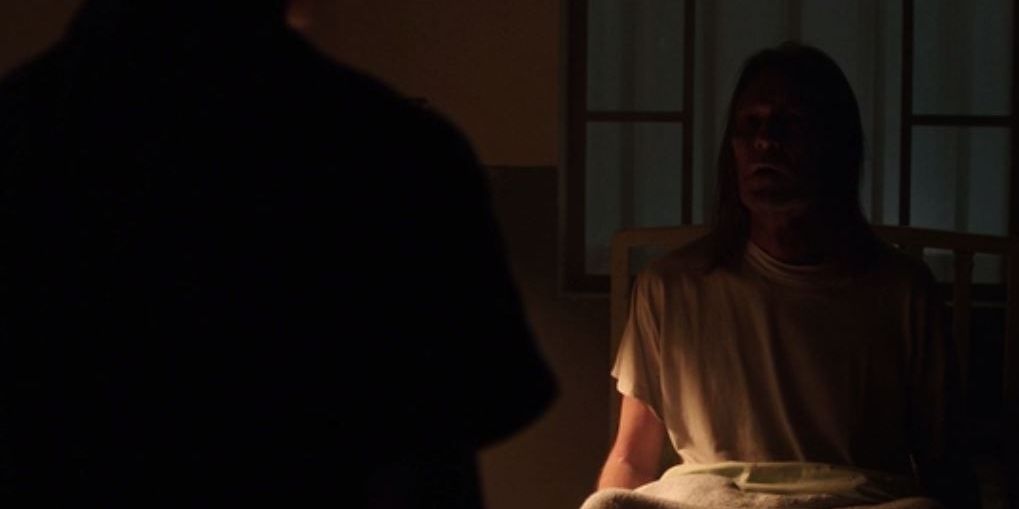 A man sits up in a hospital bed with a creepy expression in The Conjuring The Devil Made Me Do It