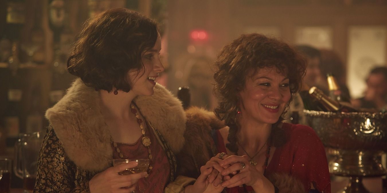 Ada and Polly at a fancy bar gathering, wearing fur and drinking in Peaky Blinders.