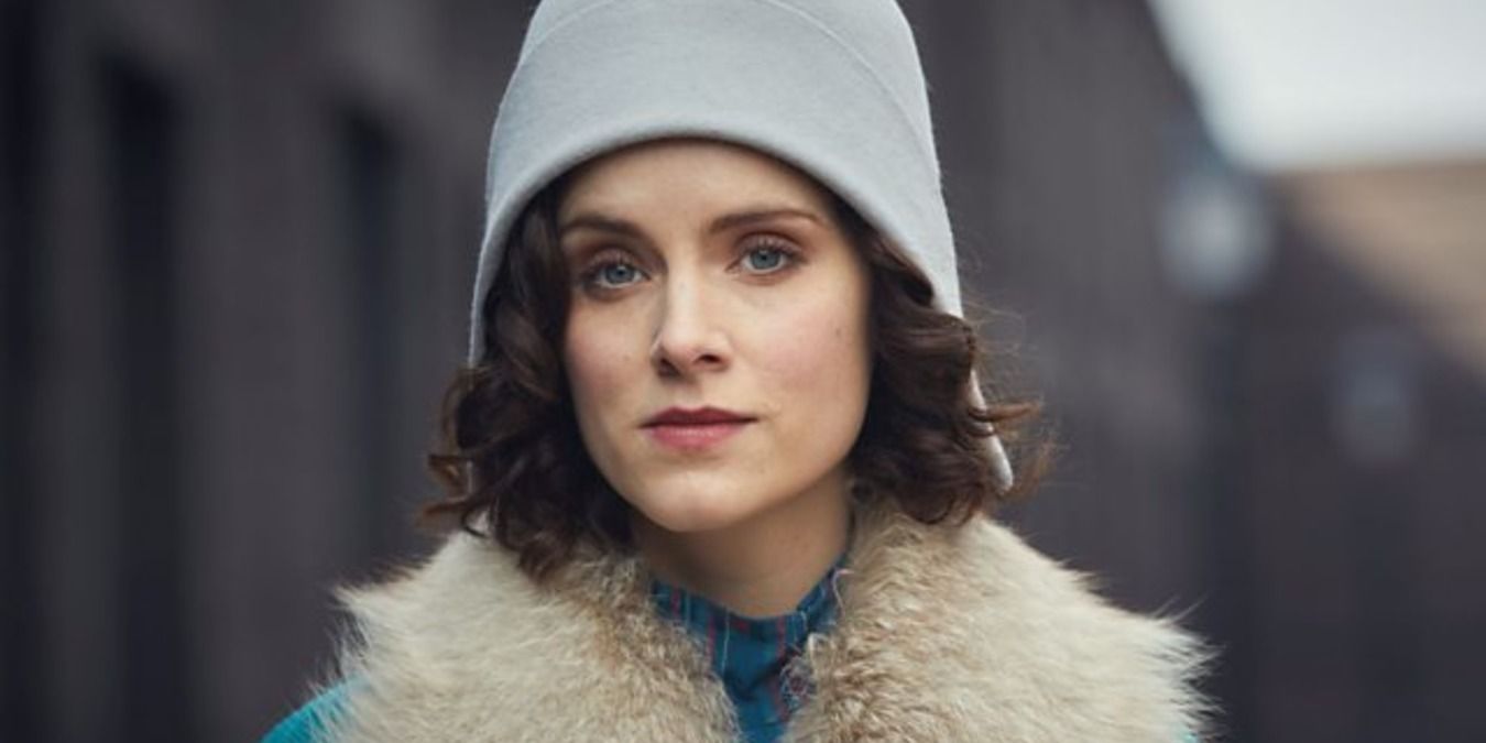 Ada standing in the streat in a hat and fur coat in Peaky Blinders