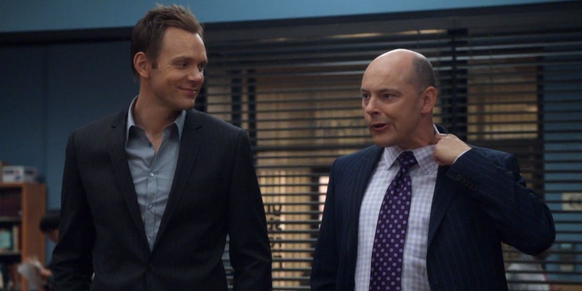 Alan Connor loosens his collar while standing next to Jeff in Community