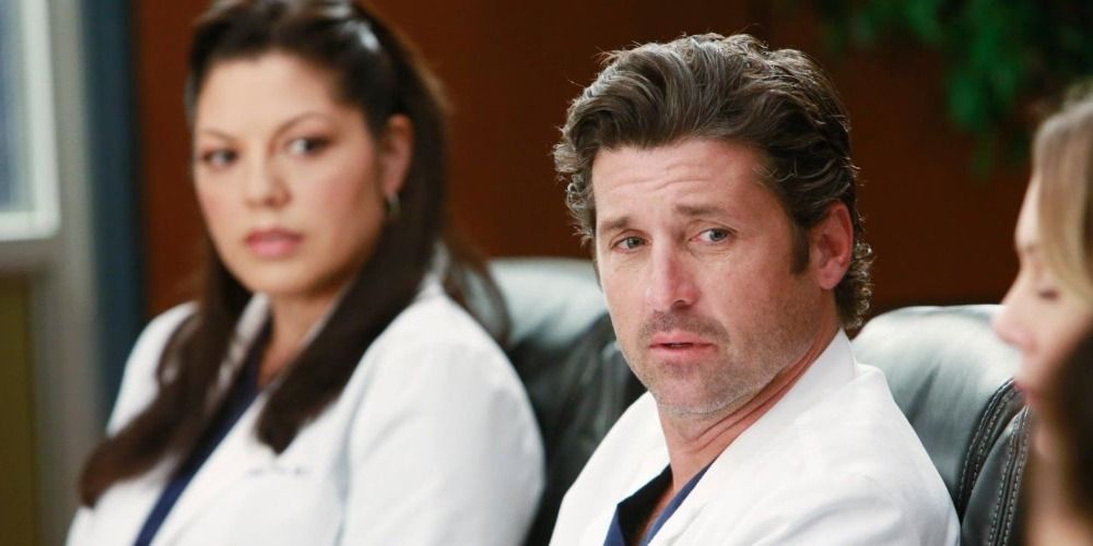 An image of Callie and Derek sitting in the boardroom in Grey's Anatomy.