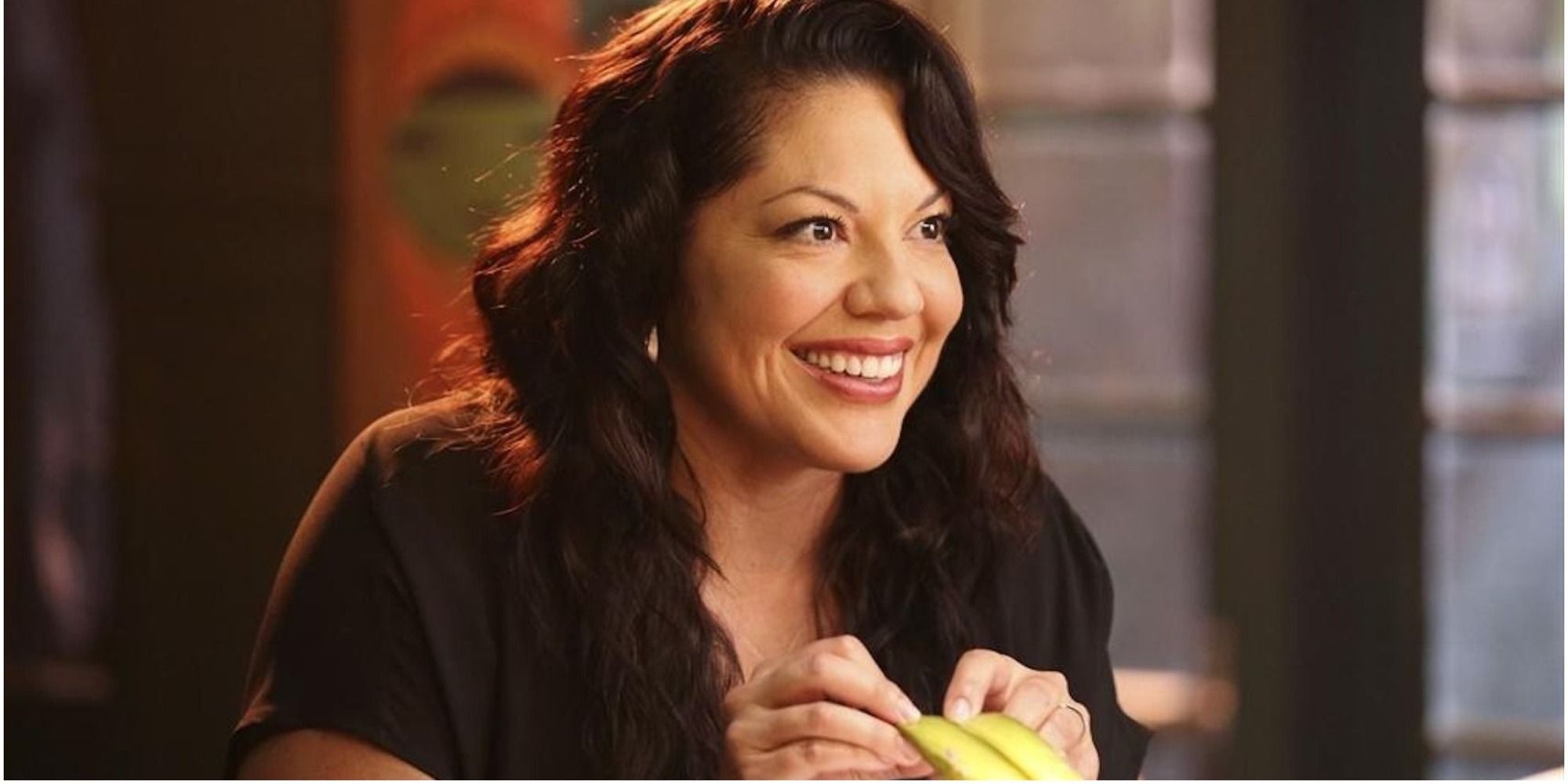 An image of Callie smiling to someone off screen while she has a drink at Joe's Bar in Grey's Anatomy