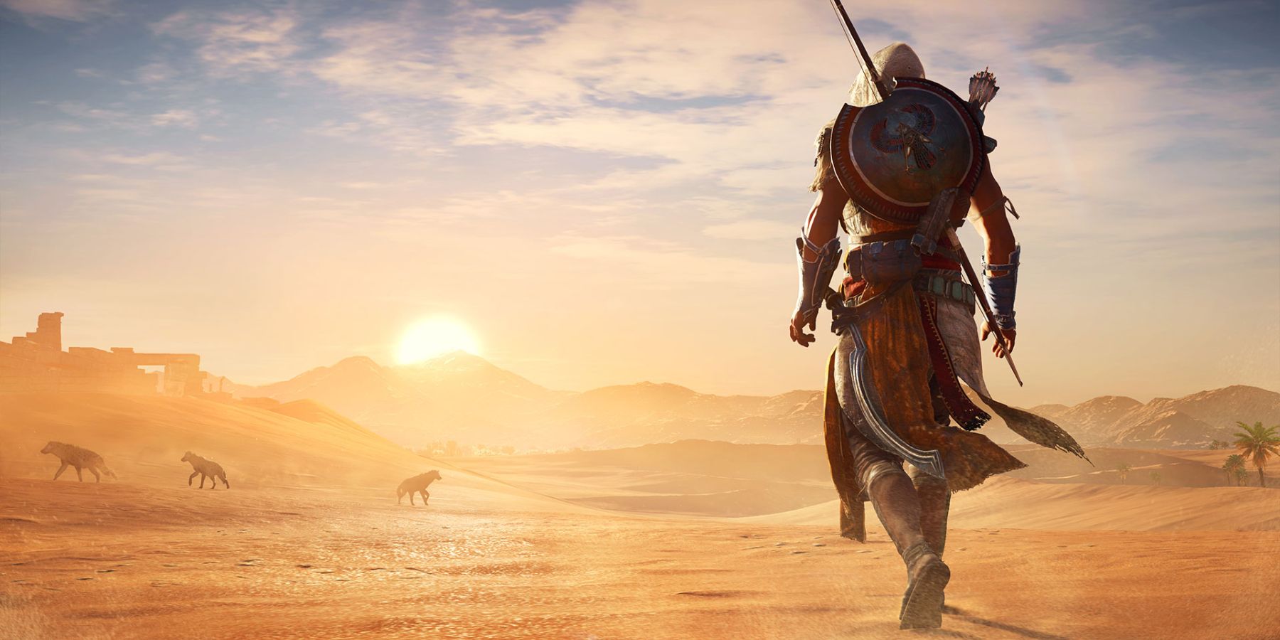 Bayek stands in the desert as the sun sets in Assassin's Creed: Origins