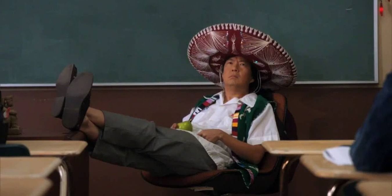 Ben Chang sentado na cadeira na frente da classe, vestindo um sombrero