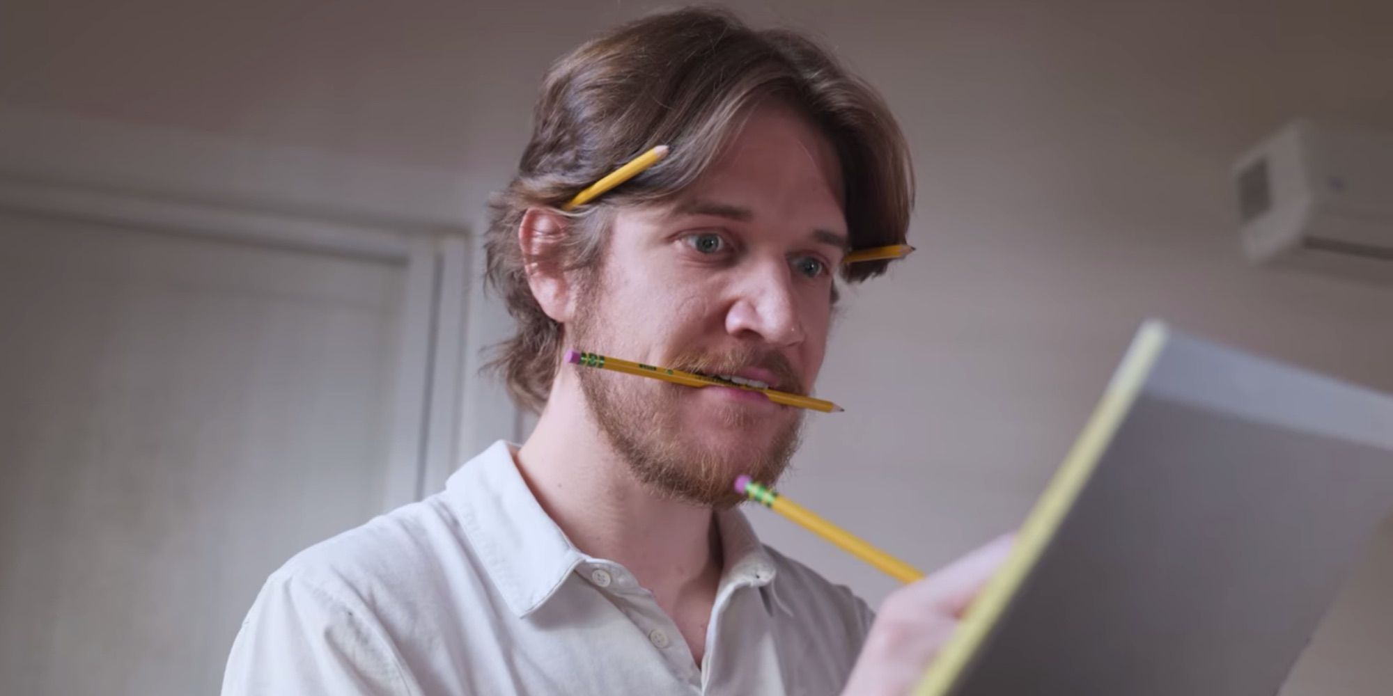Bo with a bunch of pencils all over his face, jotting on a notepad