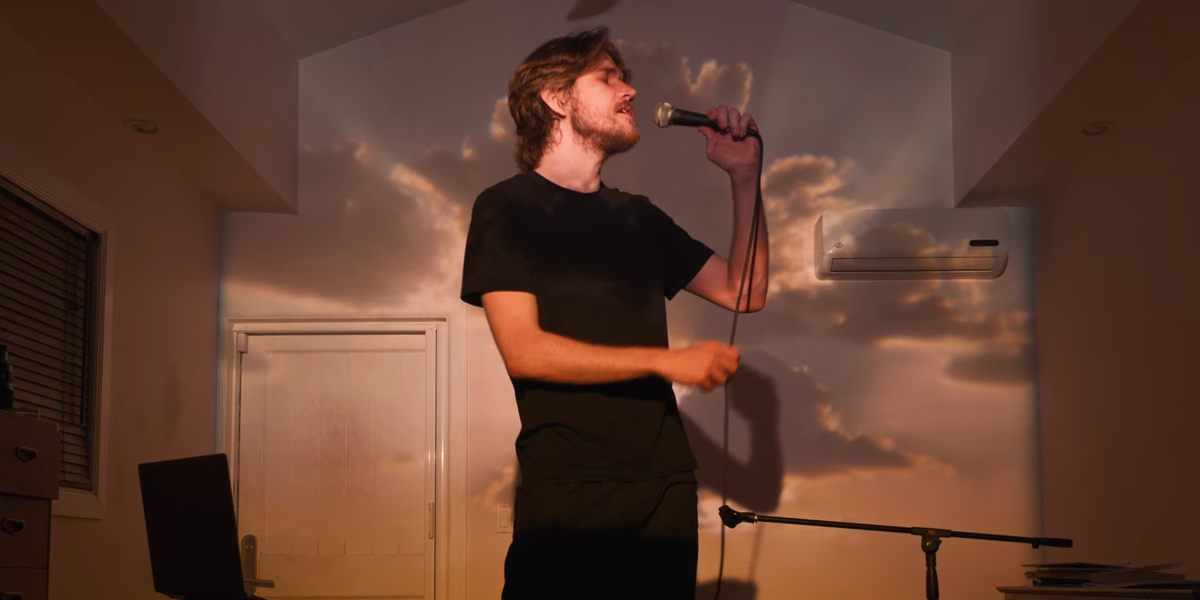 Bo Burnham singing with a microphone in an empty room