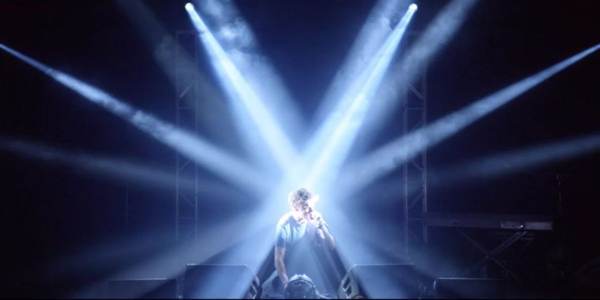 Sveral lights shine on Bo Burnham as he sings
