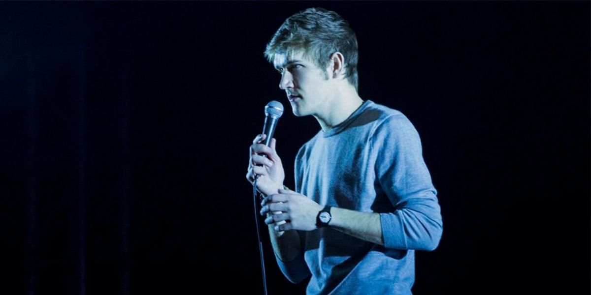 Bo Burnham talking on a microhpone and walking down a stage