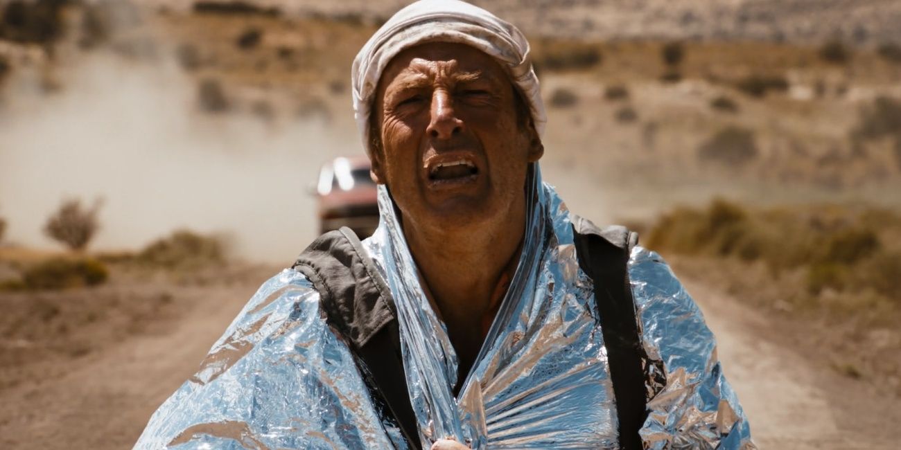 Saul Goodman wearing foil blanket in the desert with car coming behind him