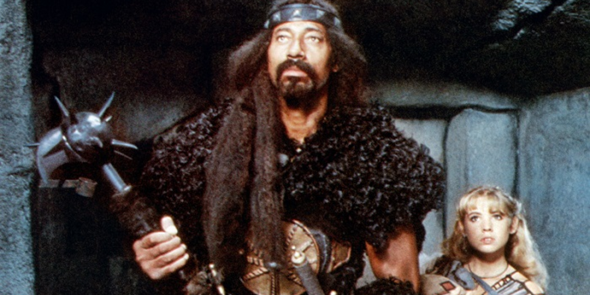 Wilt Chamberlain as Bombaata in Conan The Destroyer with a woman behind him