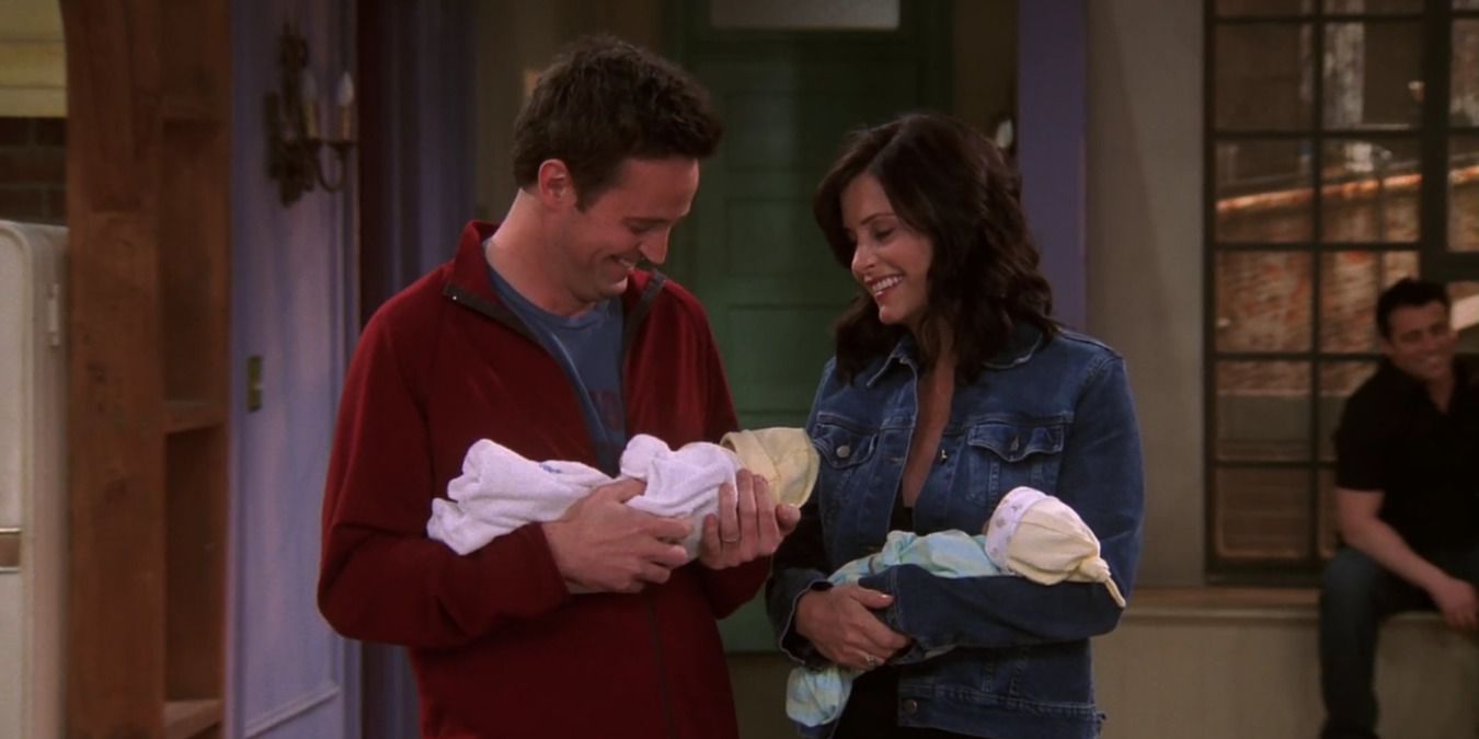 Chandler and Monica holding their twins in the apartment
