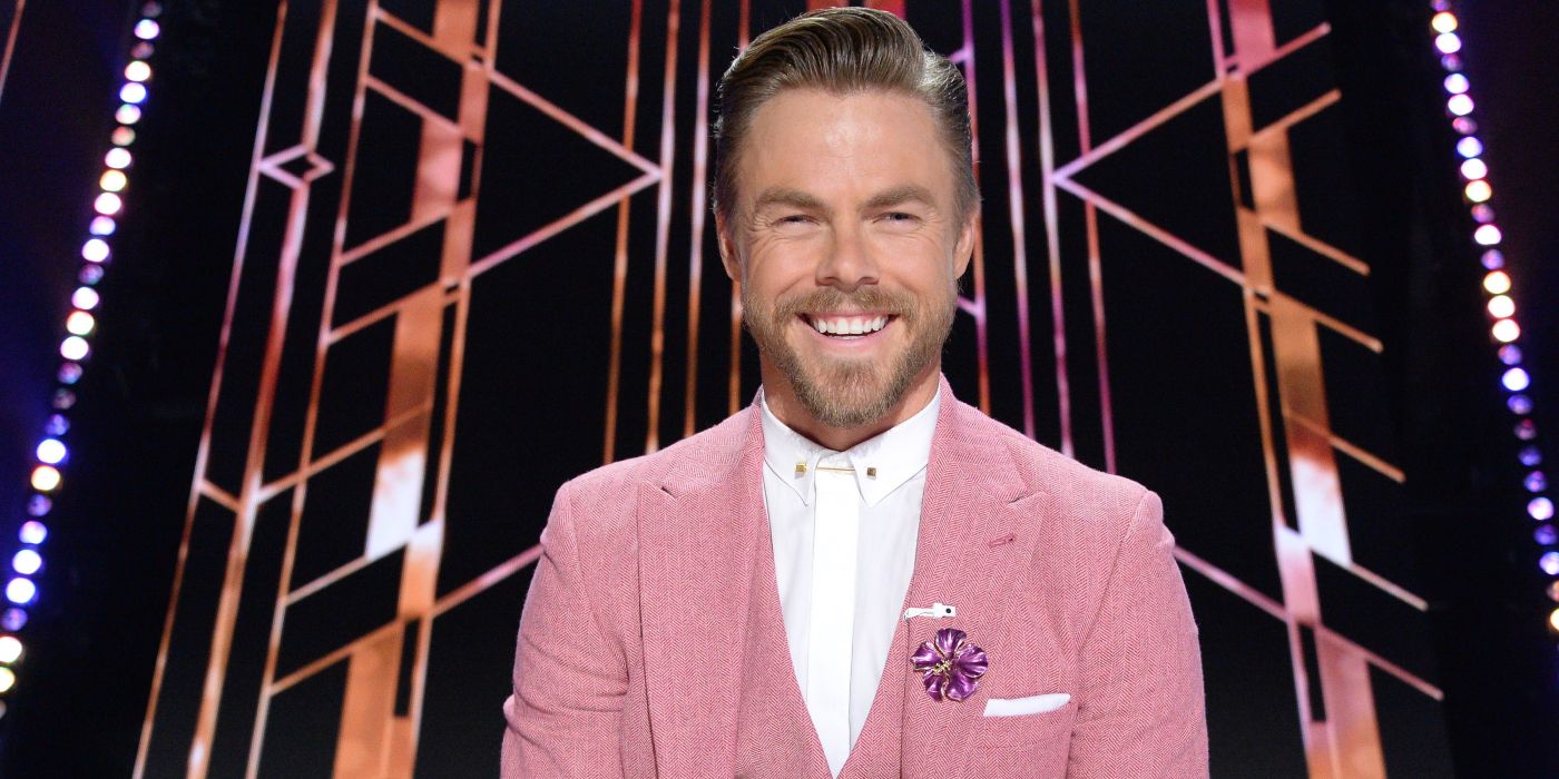 Derek Hough on Dancing With The Stars wearing pink jacket smiling 