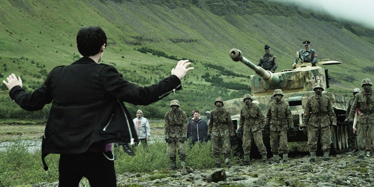 A young man raises his hands as an group of zombie soldiers approaches