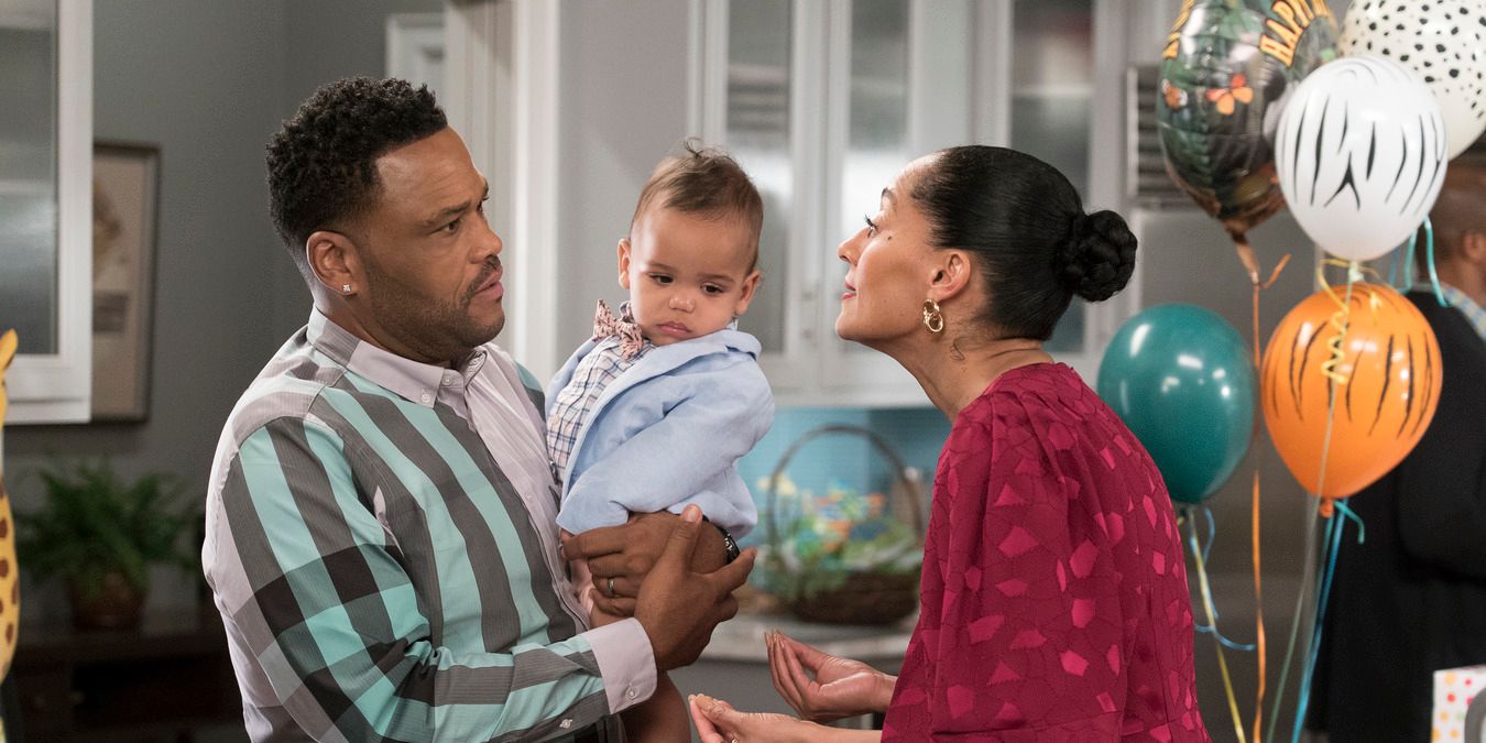 Dre holding their baby, talking to Angel in the kitchen