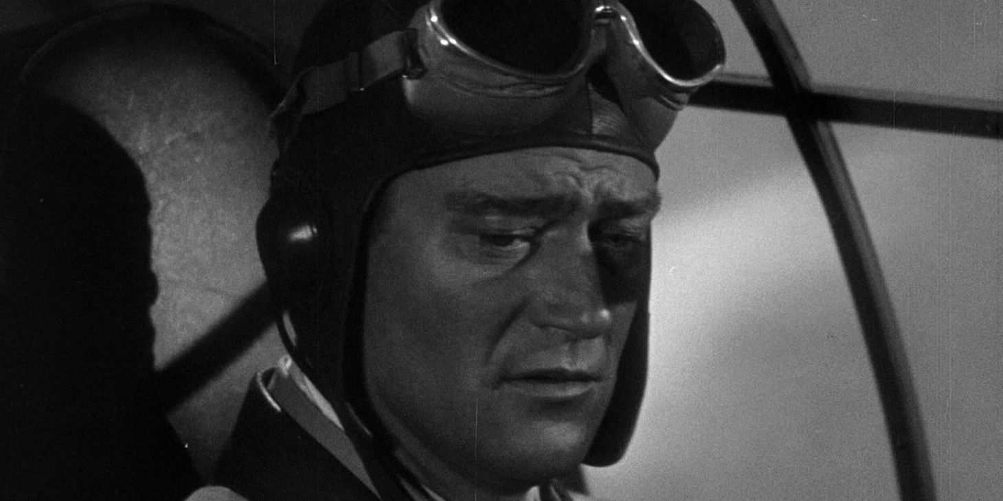 John Wayne sits in the cockpit of a Flying Tigers military plane.