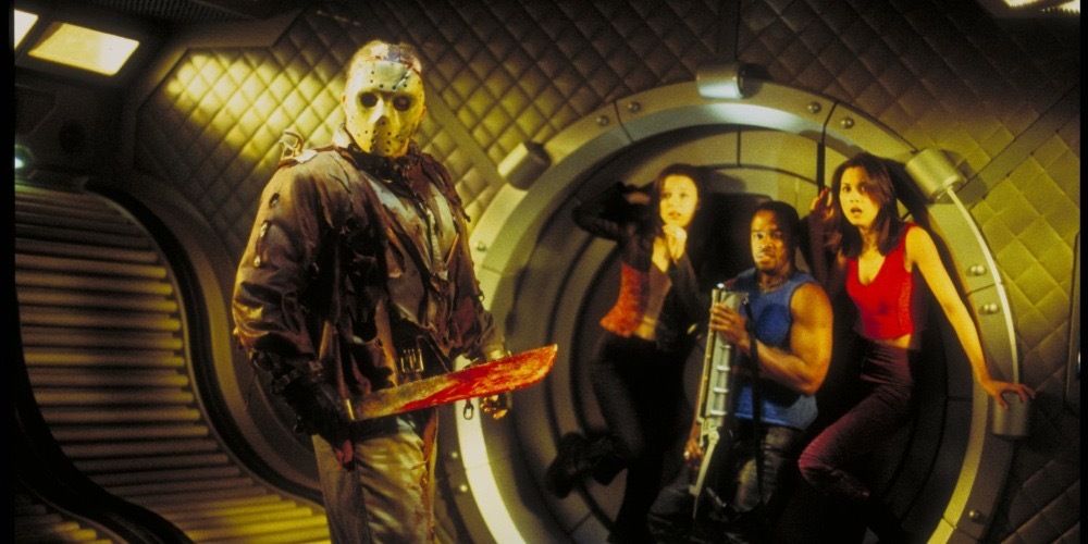 Three young people cower in fear as Kane Hodder's Jason stands before them in Jason X 2002