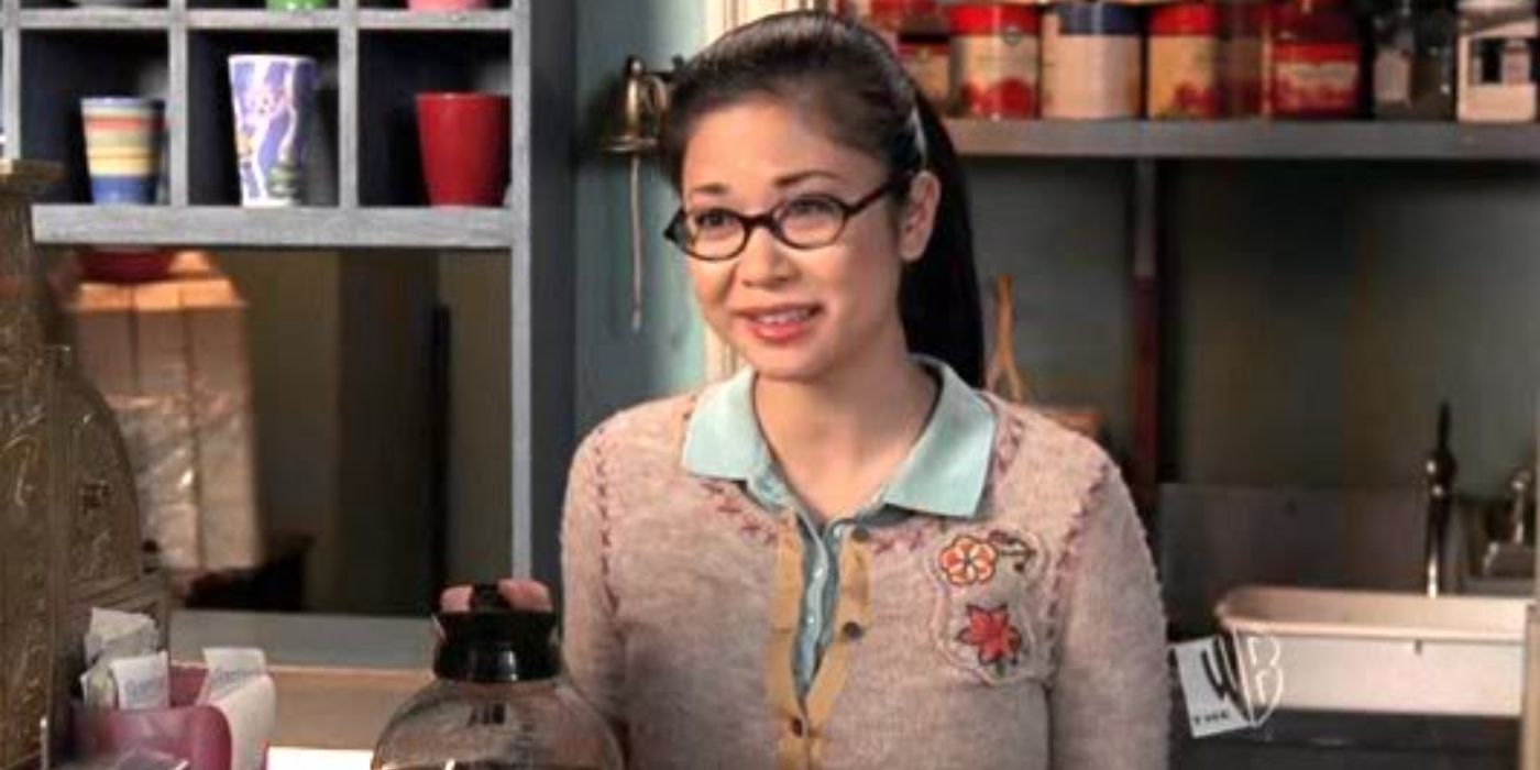 Lane Kim holding a pot of coffee and standing behind the counter at Luke's diner on Gilmore Girls