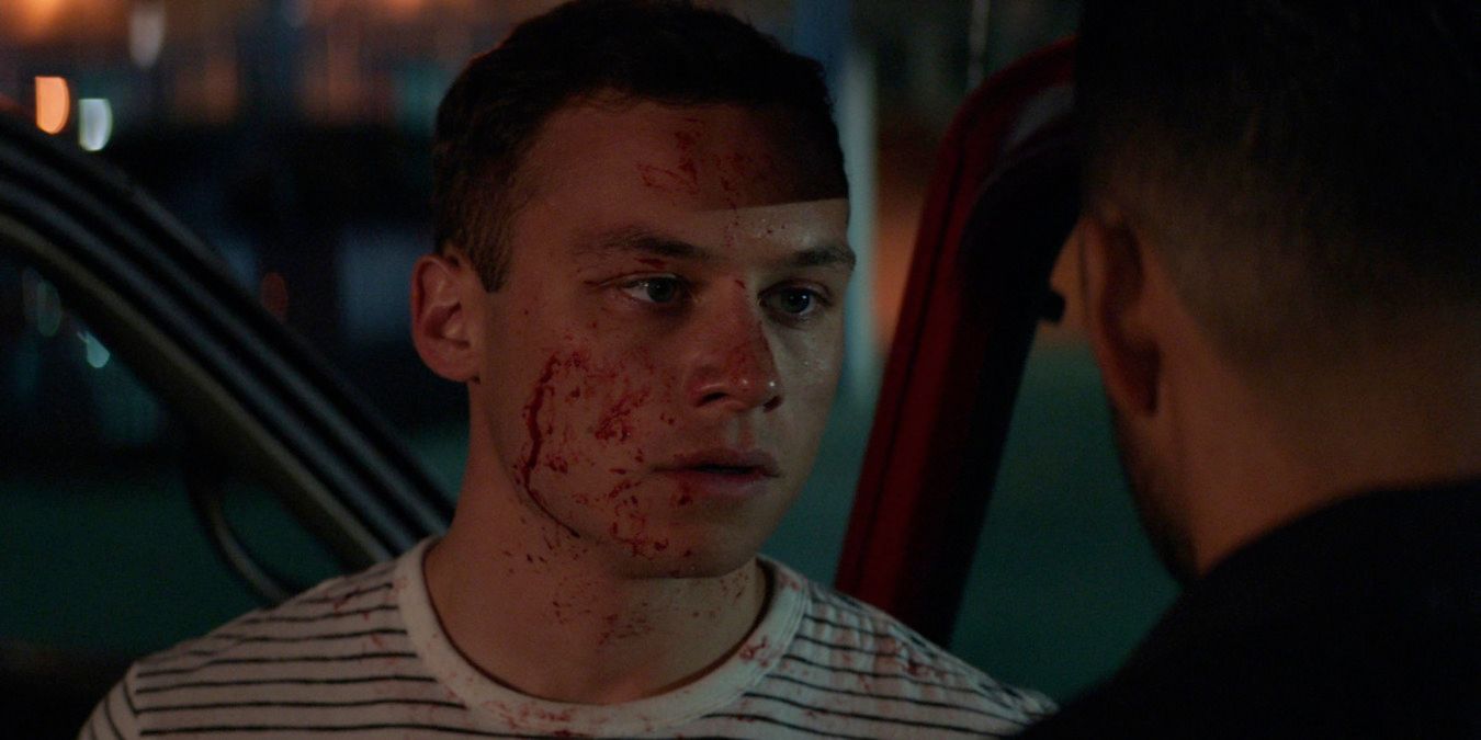 J standing outside his truck at night, covered in blood after shooting Mia