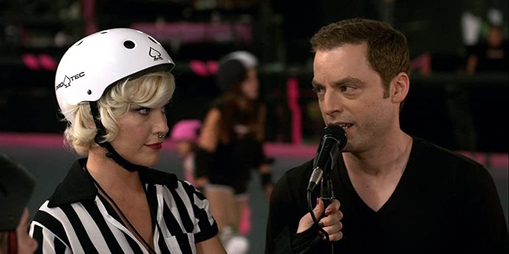 Jessica Kiper as a roller derby referee pointing a mic towards a man in a still from Weeds 