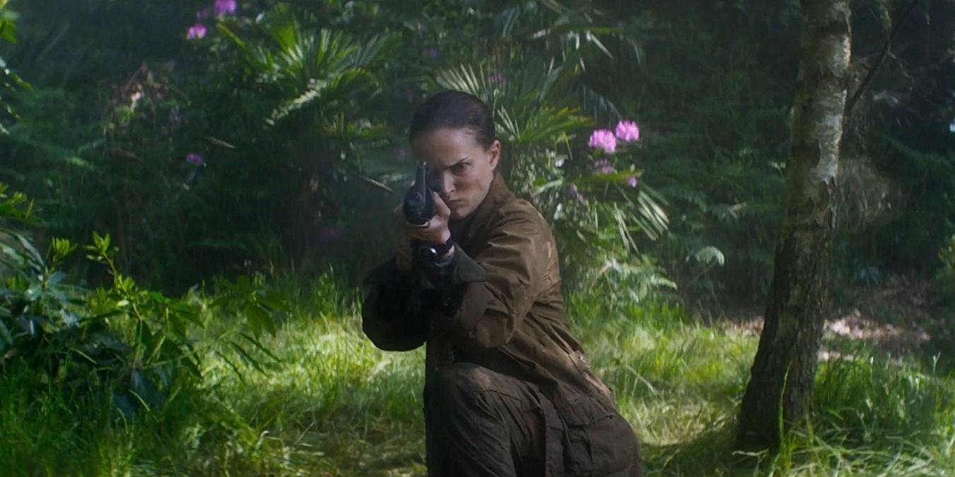 Lena kneeling in the forest, holding her gun up in Annihilation.
