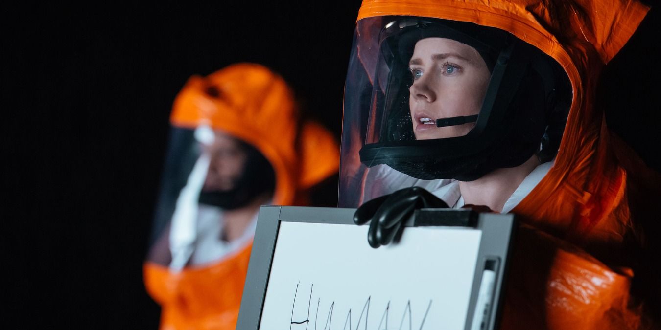 Louise in a hazmat suit, holding a sign that says human in Arrival.