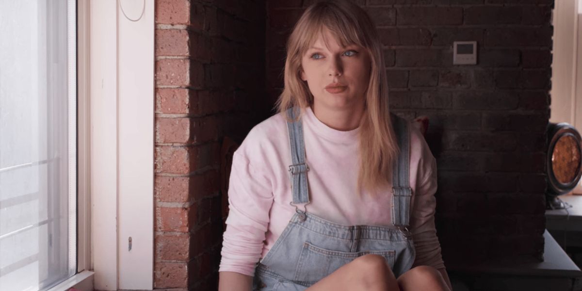 Taylor Swift sitting by window in overalls in Miss Americana