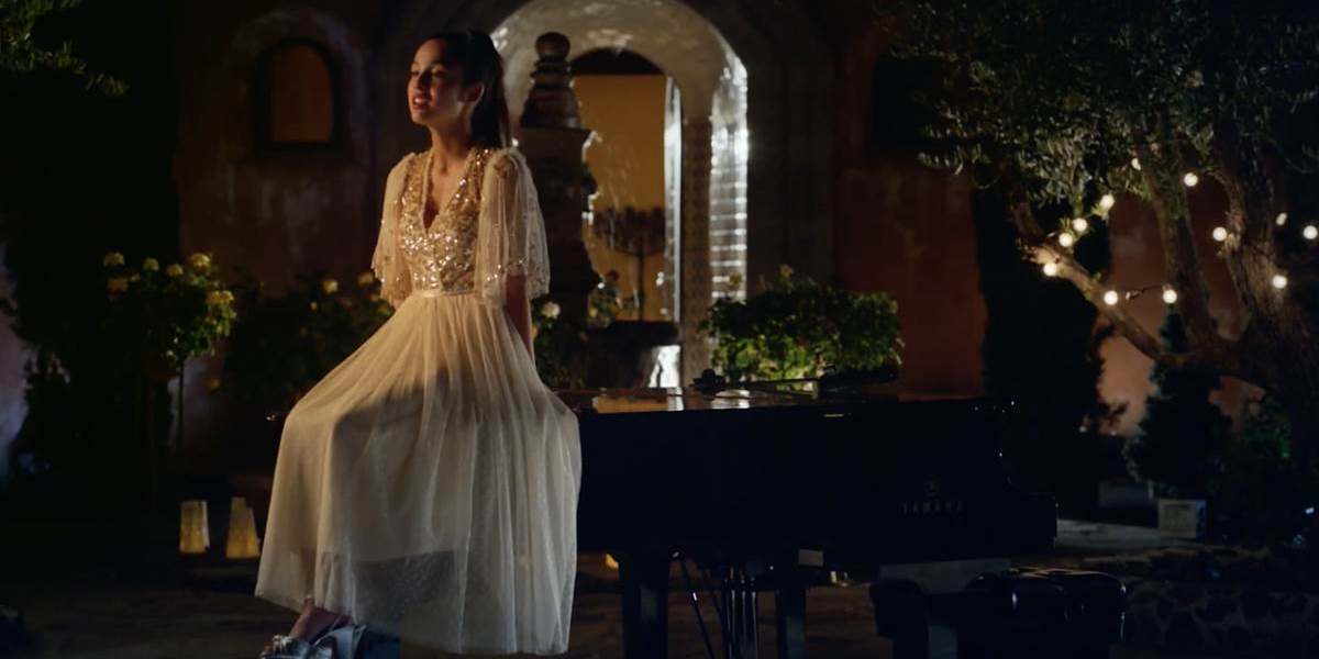 Olivia Rodrigo sings on top of a piano