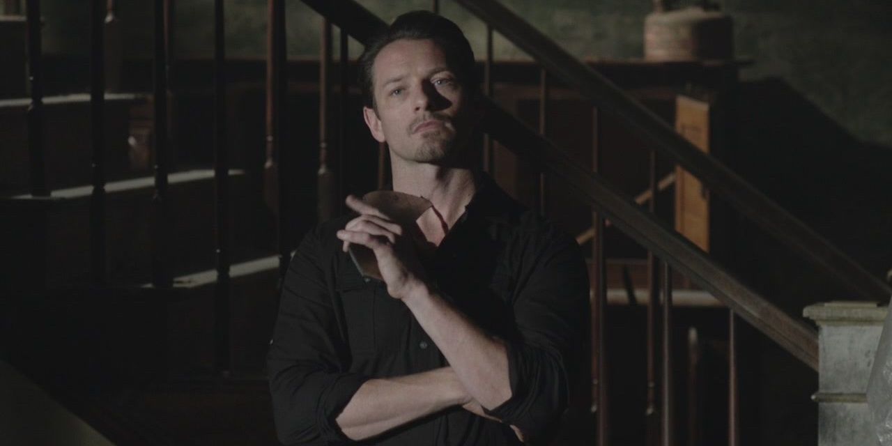 Peter Hale from Teen Wolf absently holds a shard of mirror to his neck before throwing it