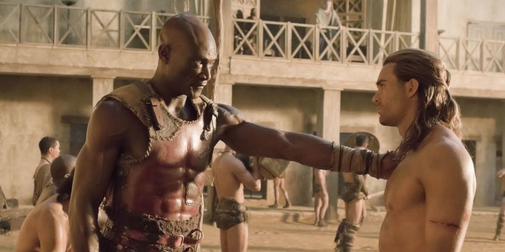 Peter Mensah's Oenomaus touching Gannicus' shoulder in Spartacus Blood and Sand