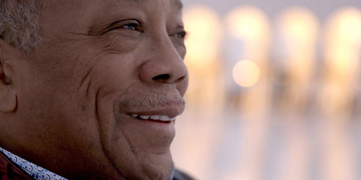 Quincy Jones smiling close-up with city backdrop in Quincy